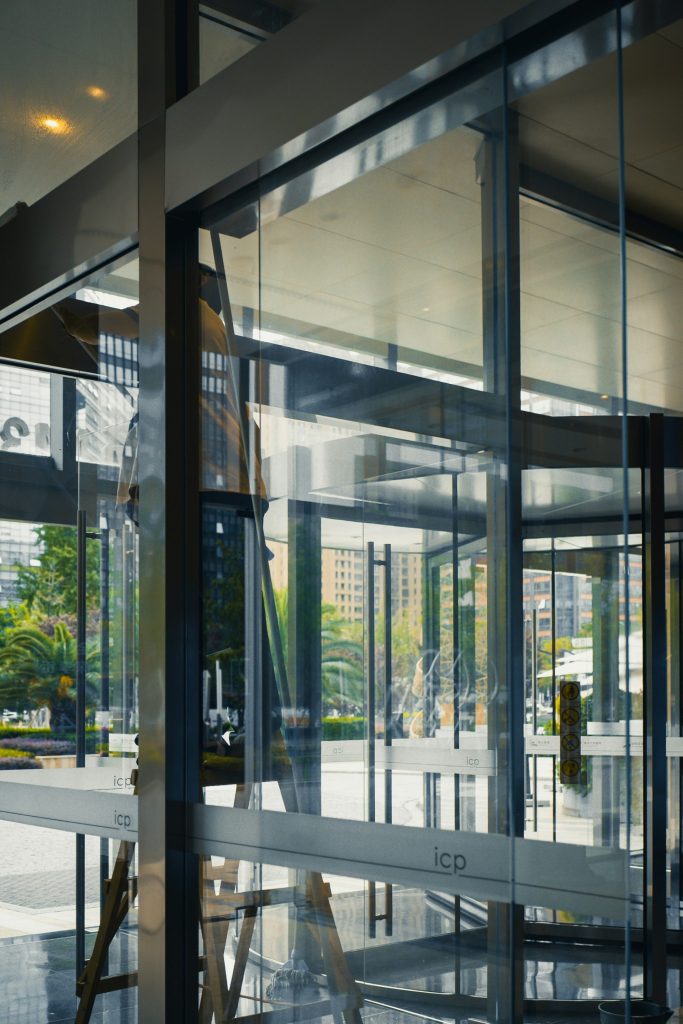 a large glass building with a clock on it's side