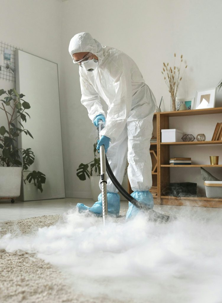 Eine Person in Schutzkleidung reinigt einen Teppich.